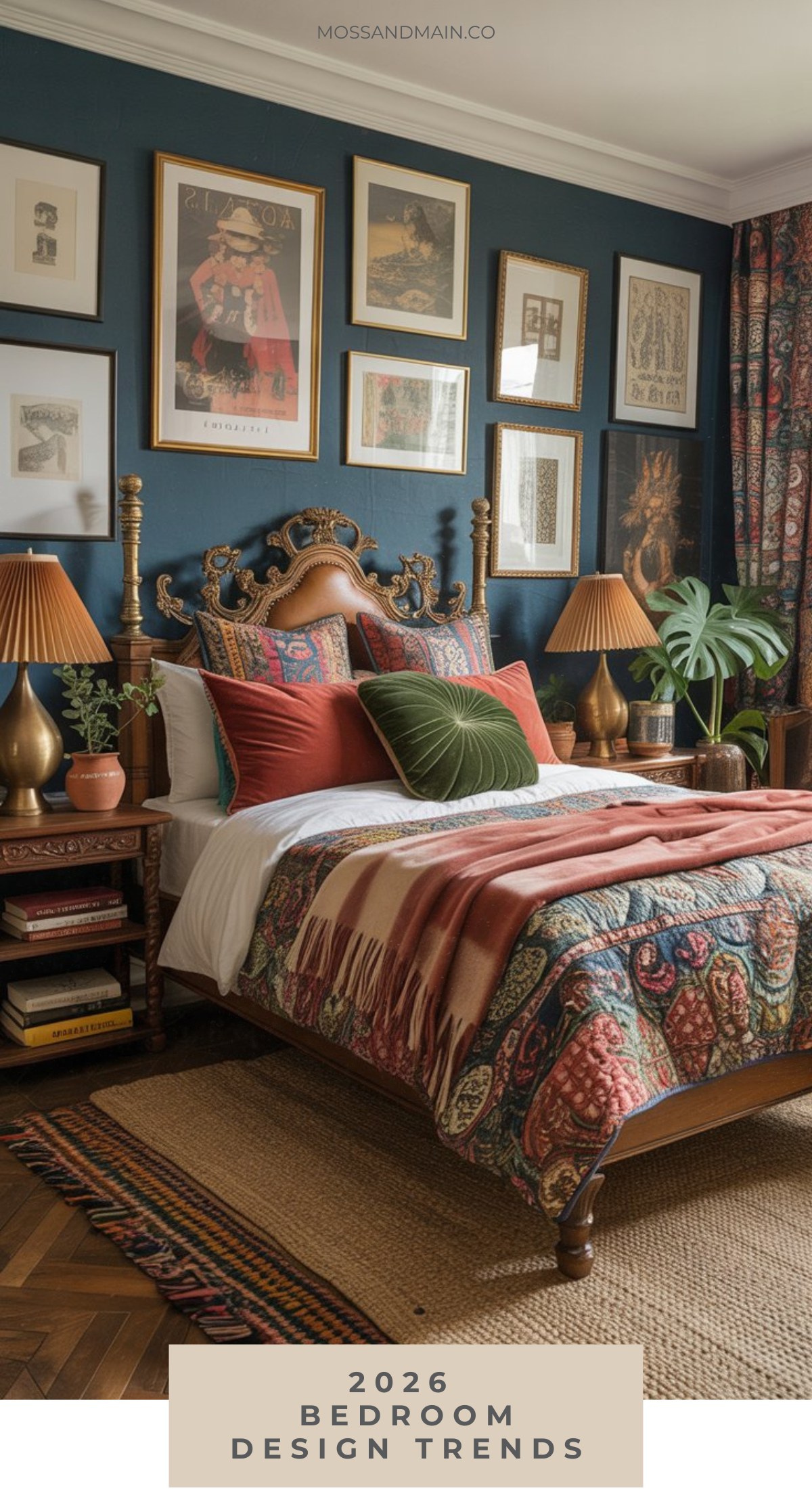 A stylish maximalist bedroom features a vintage wooden bed with colorful patterned bedding, matching pillows, and throws. The dark blue wall is decorated with framed art—showcasing the latest bedroom decor trends for 2026.