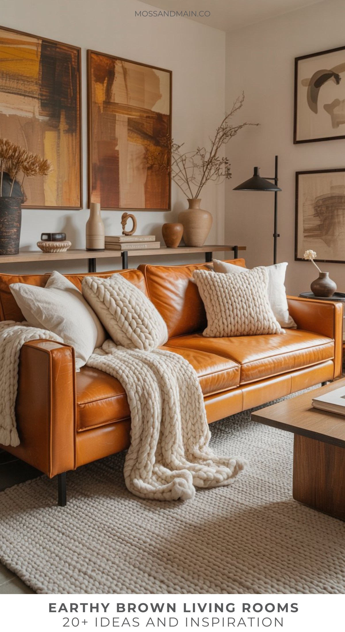 A caramel brown leather sofa, cream knit blankets, a textured rug, and earth-toned art come together to inspire cozy brown living room ideas with a modern touch and neutral decor.