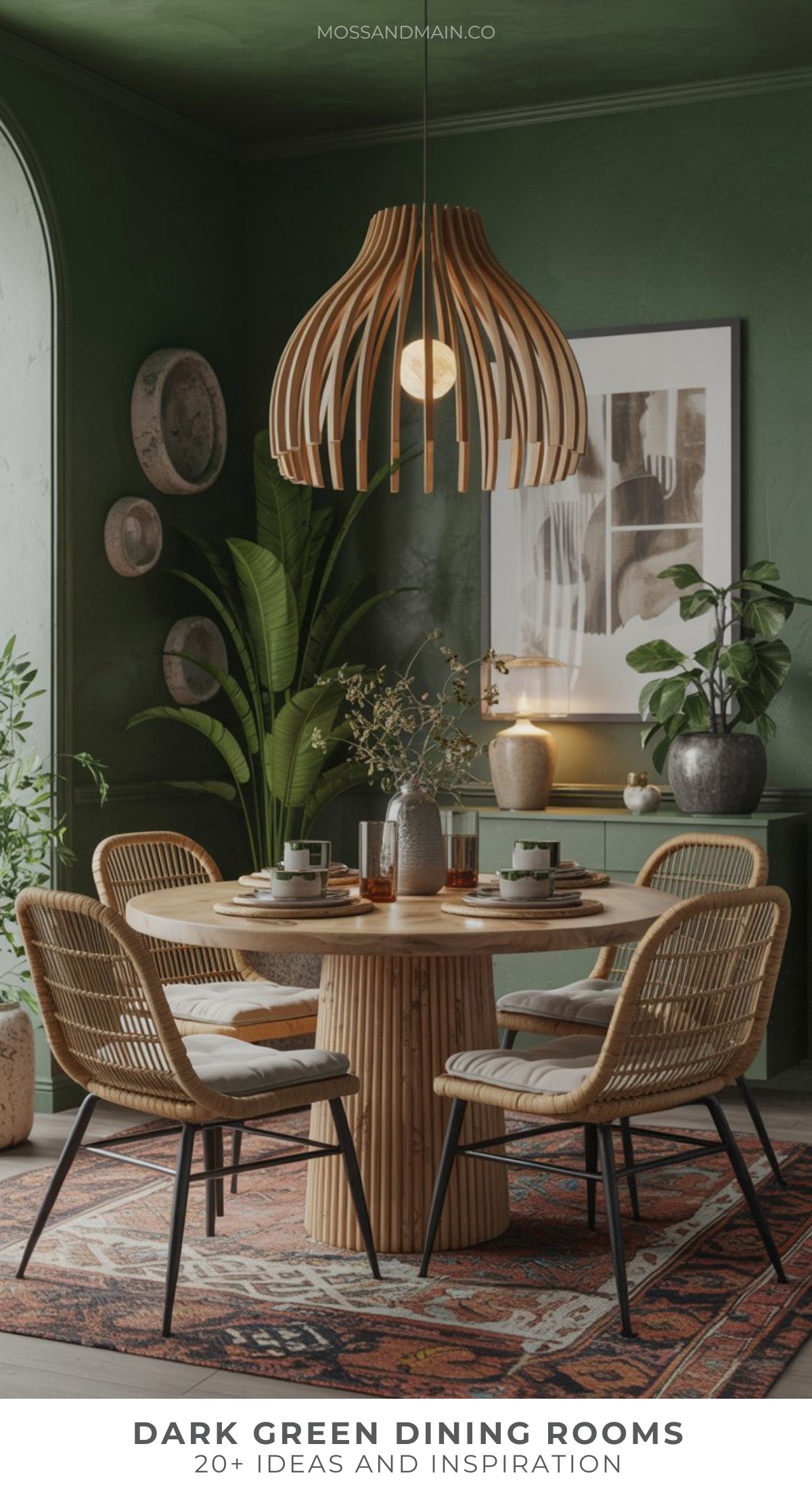 A stylish dark green dining room features a round wooden table, four wicker chairs, large leafy plants, a modern wooden pendant light, decorative plates on the wall, and a patterned rug.