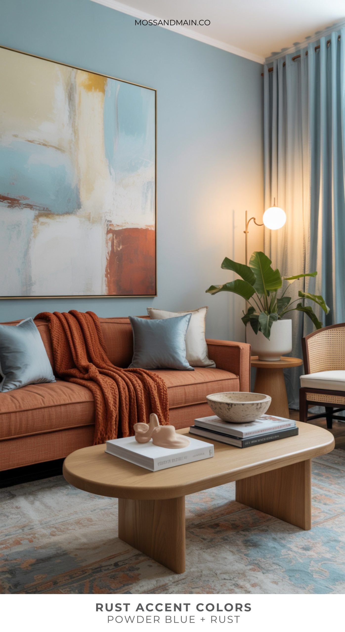 A modern living room with rust home decor, including a rust-colored sofa and throw blanket, powder blue pillows, a light wood coffee table, a large abstract painting, a potted plant, and soft blue curtains.