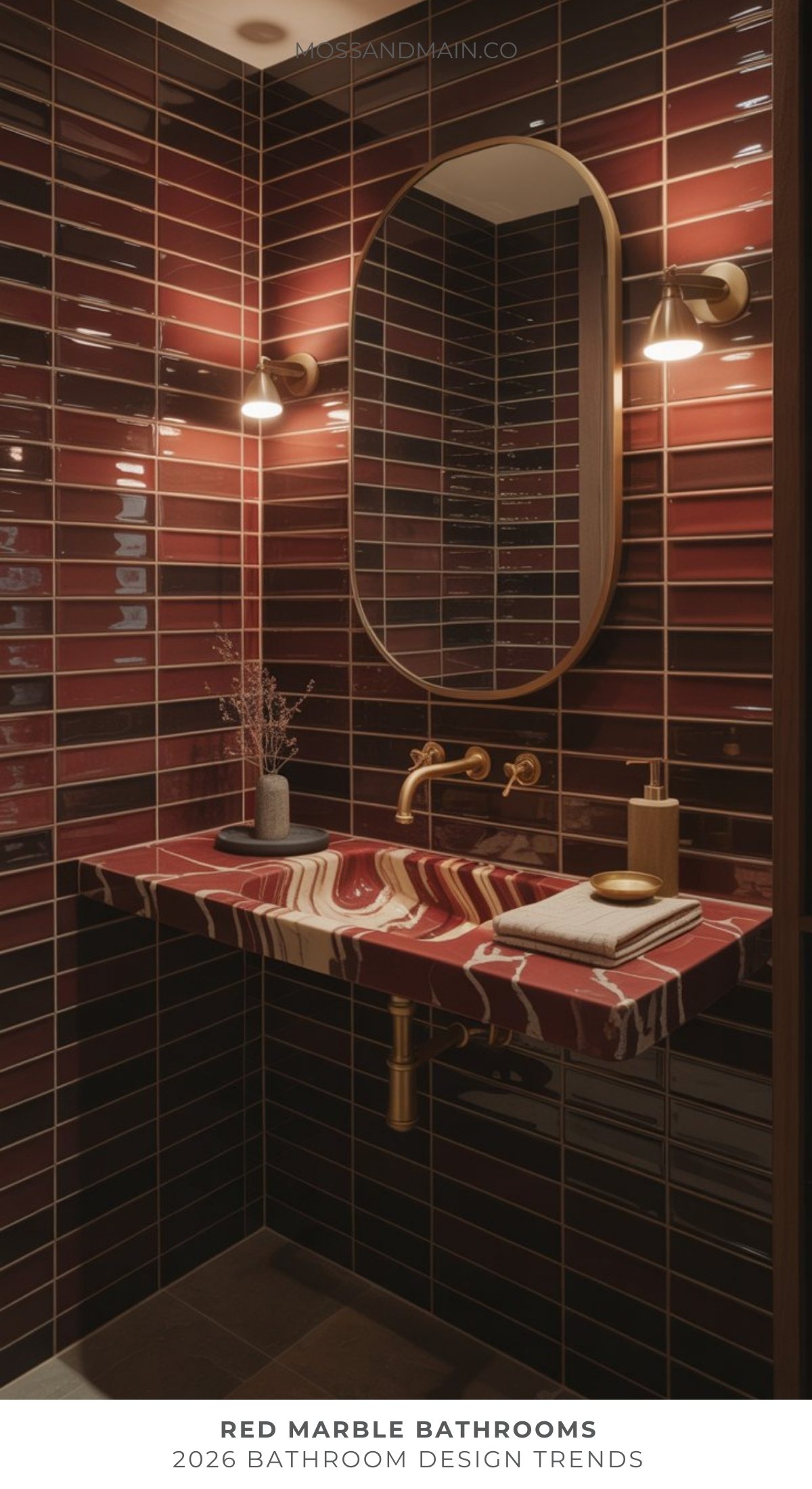 A modern bathroom showcases the bold bathroom trend with glossy red and burgundy tiles, a red marble countertop with a gold faucet, an oval mirror, wall sconces, and neatly arranged towels and decor.