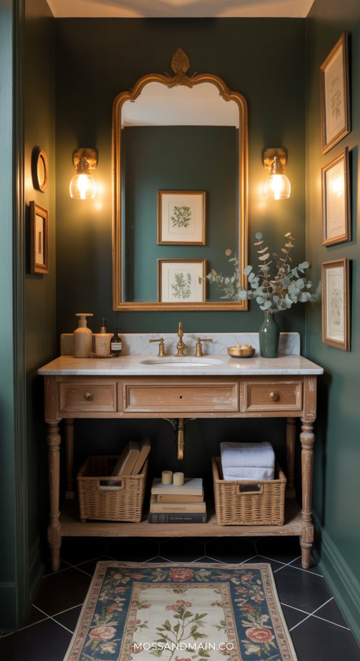A moody bathroom with dark green walls, a vintage wood vanity, marble countertop, gold fixtures, an ornate mirror, wall sconces, framed art, and a floral rug on black tile. Towels and decor are neatly arranged for elegant inspiration.