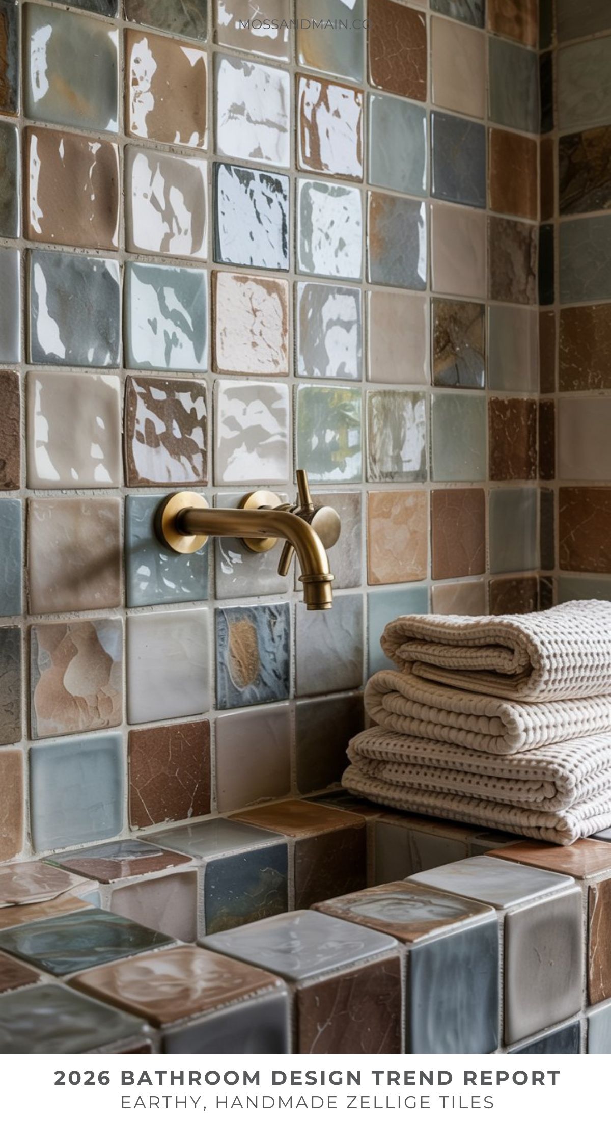 A bathroom features earthy, handmade zellige tiles in natural shades—perfect Pinterest bathroom inspiration. A modern brass faucet mounts above a tiled counter with neatly folded cream towels, capturing the essence of upcoming bathroom trends 2026.