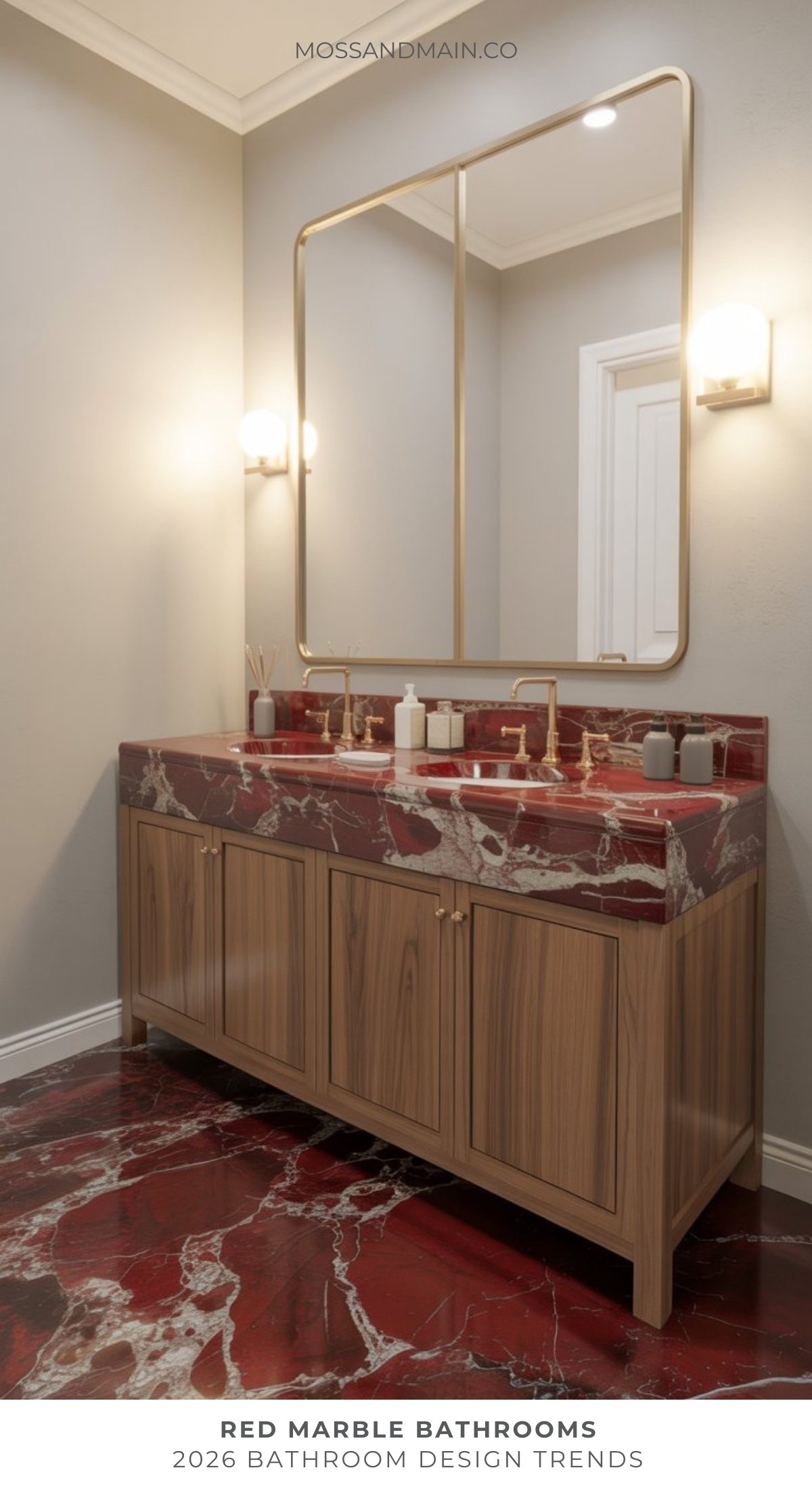 A modern bathroom trend features a wooden vanity with a red marble countertop and matching red marble floor, a large rectangular mirror, and wall-mounted lights. Neutral walls complete this bold bathroom’s clean, elegant look.