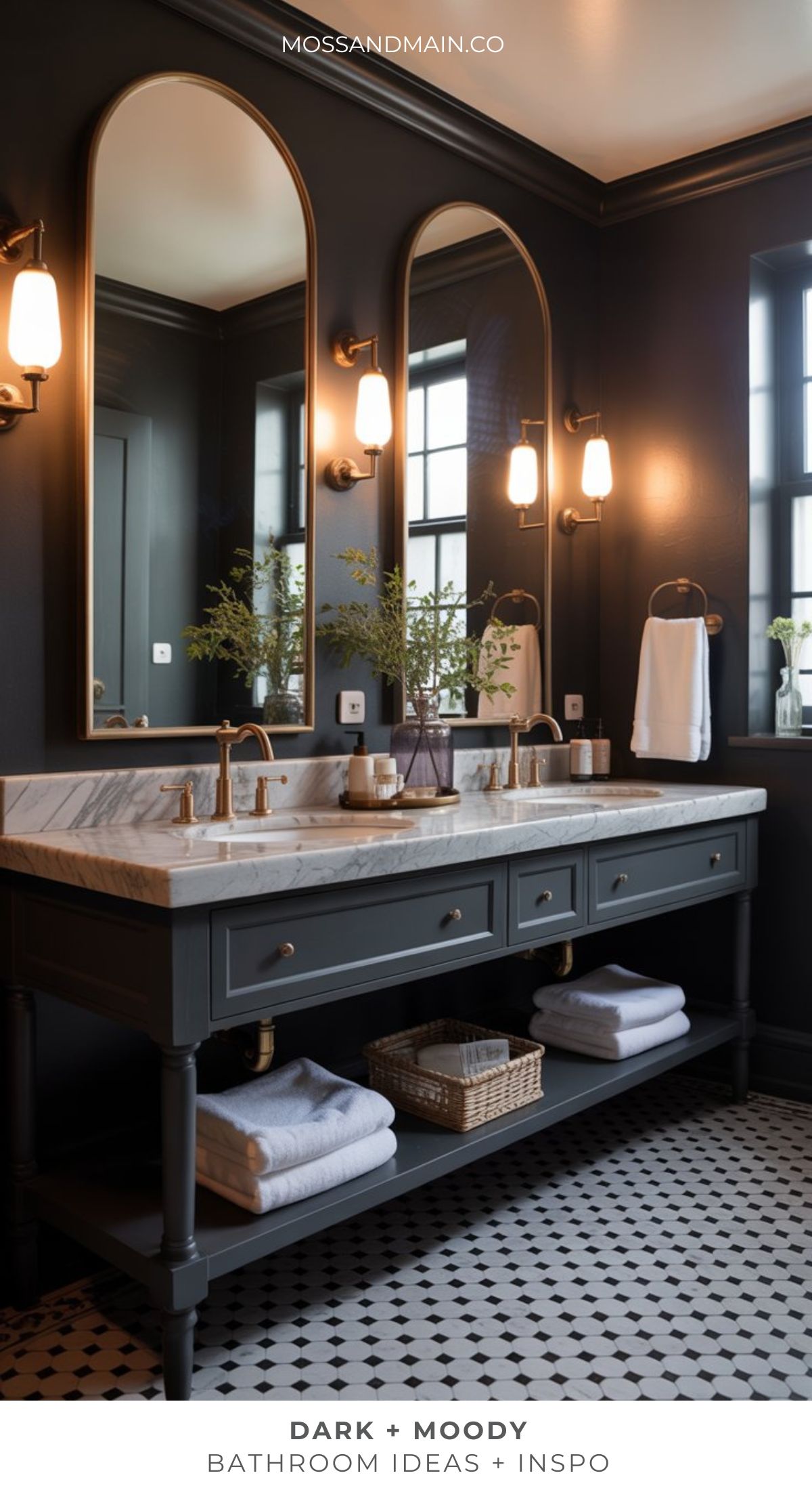 A stylish moody bathroom with dark walls, a double vanity with marble countertop, brass fixtures, two large mirrors, wall sconces, and a black-and-white tiled floor. Towels and a basket are neatly stored on the lower shelf.