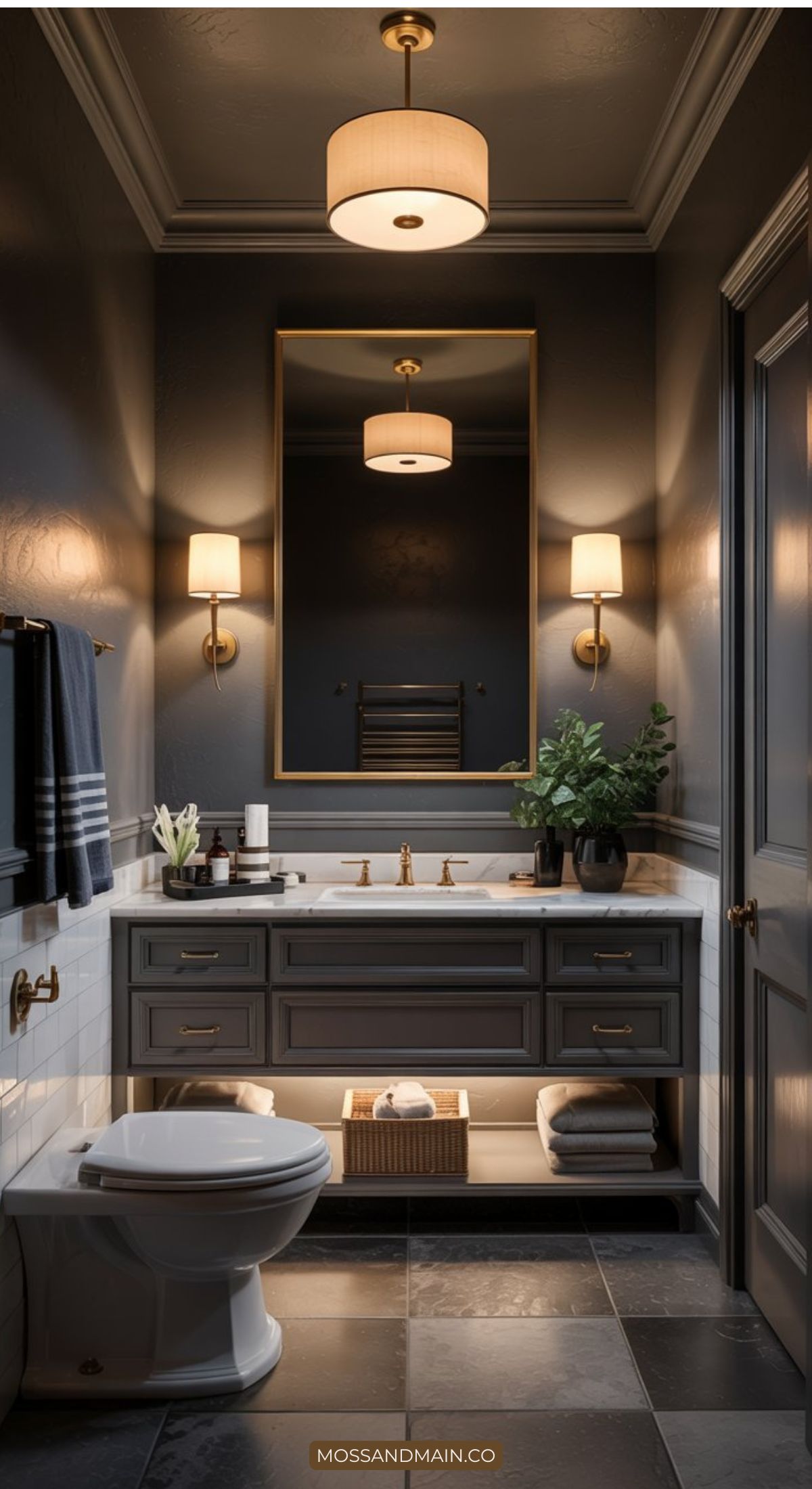 Elegant bathroom with dark gray walls, a large mirror, modern sconces, and a gray vanity with drawers. Showcasing 2026 Bathroom Trends, stylish accessories and greenery enhance the countertop and open shelf for a refined Bathroom Design.