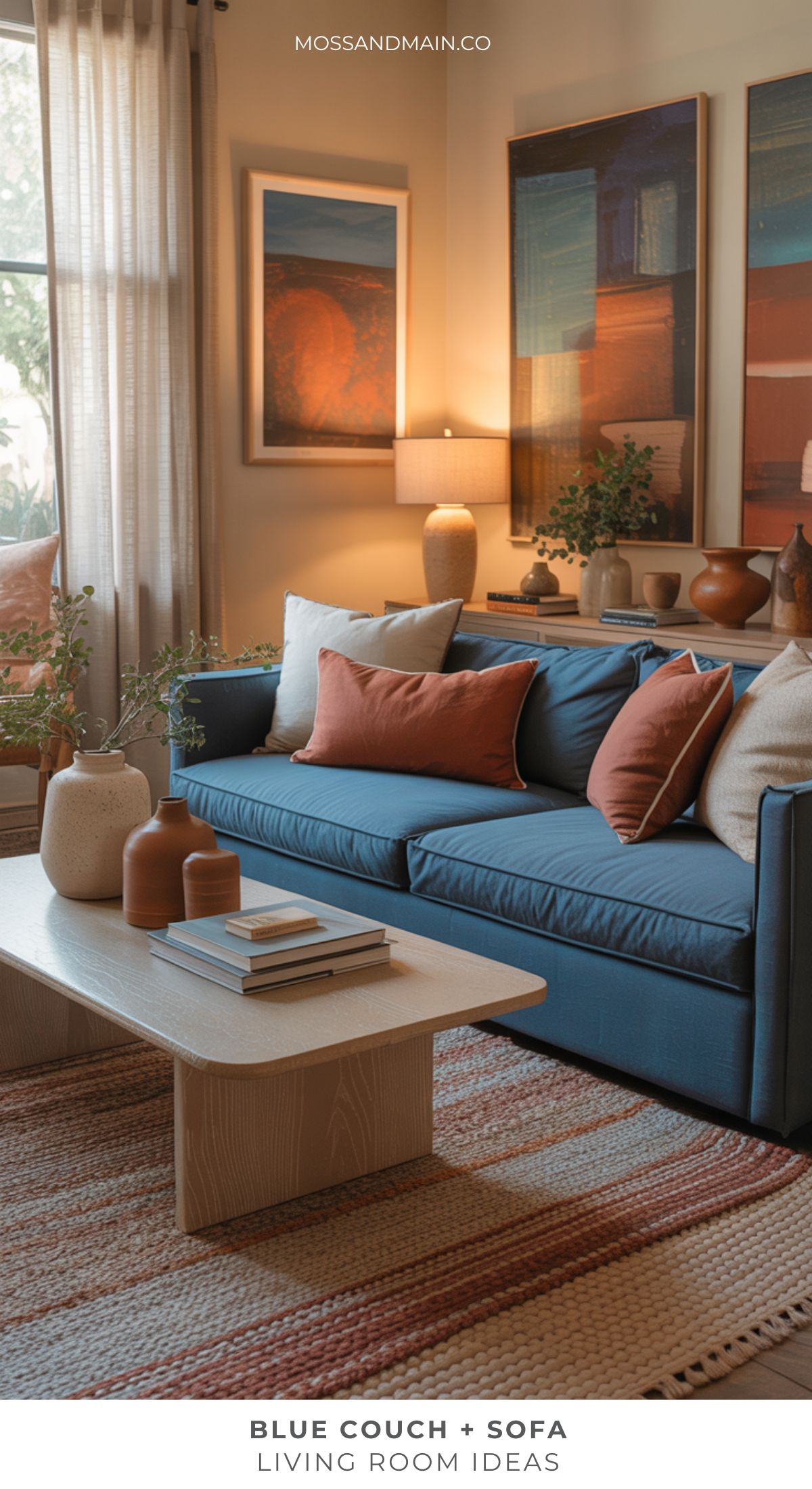 A cozy living room featuring a blue couch with rust and beige pillows, a light wood coffee table with decorative vases, woven rug, potted plants, and framed art on cream walls—perfect for inspiring fresh living room ideas.