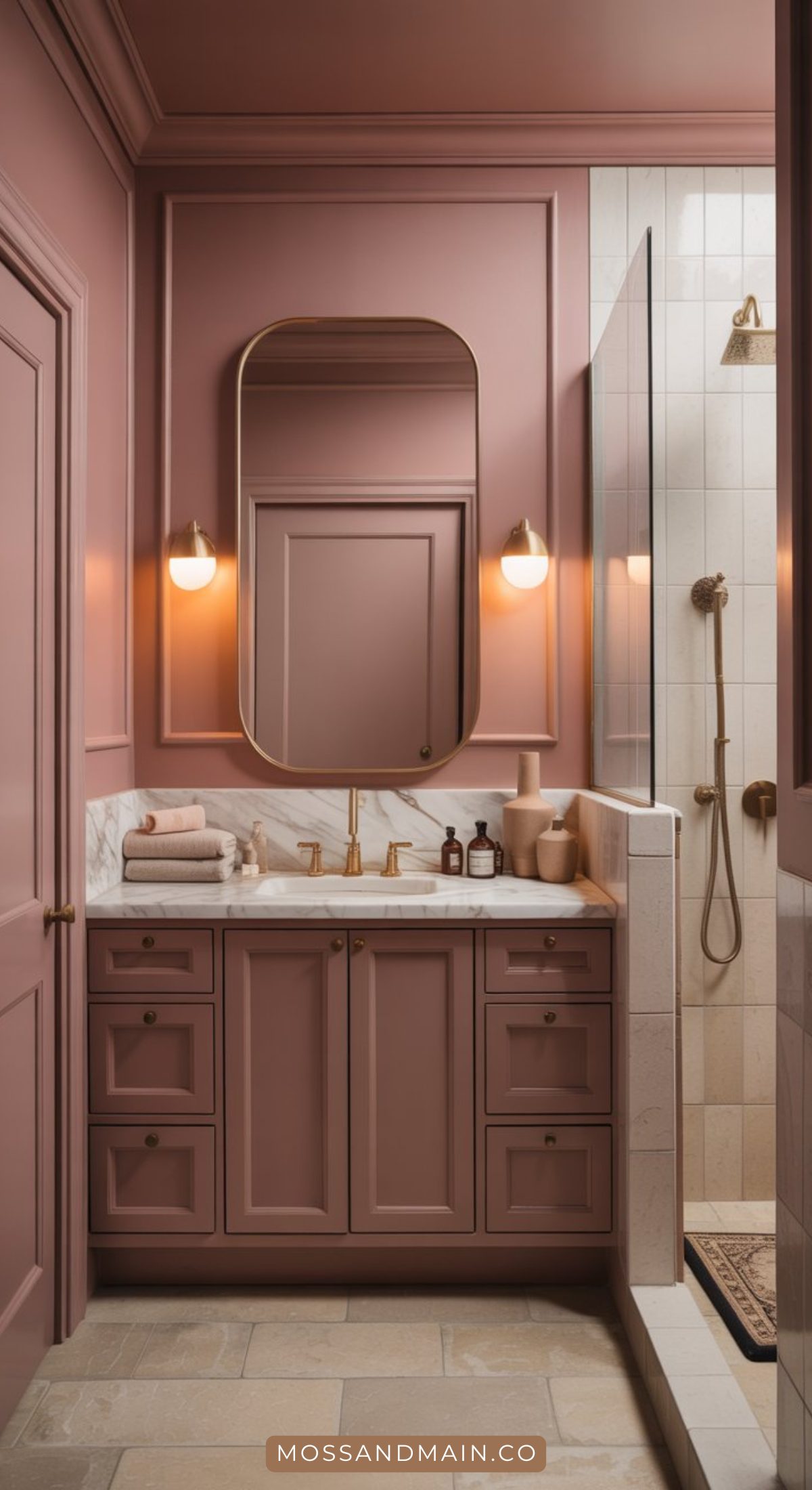 A bold bathroom showcases mauve cabinetry, a marble countertop, gold fixtures, a large oval mirror, wall sconces, and a glass-enclosed shower with matching gold hardware. Towels and toiletries sit neatly on the counter.