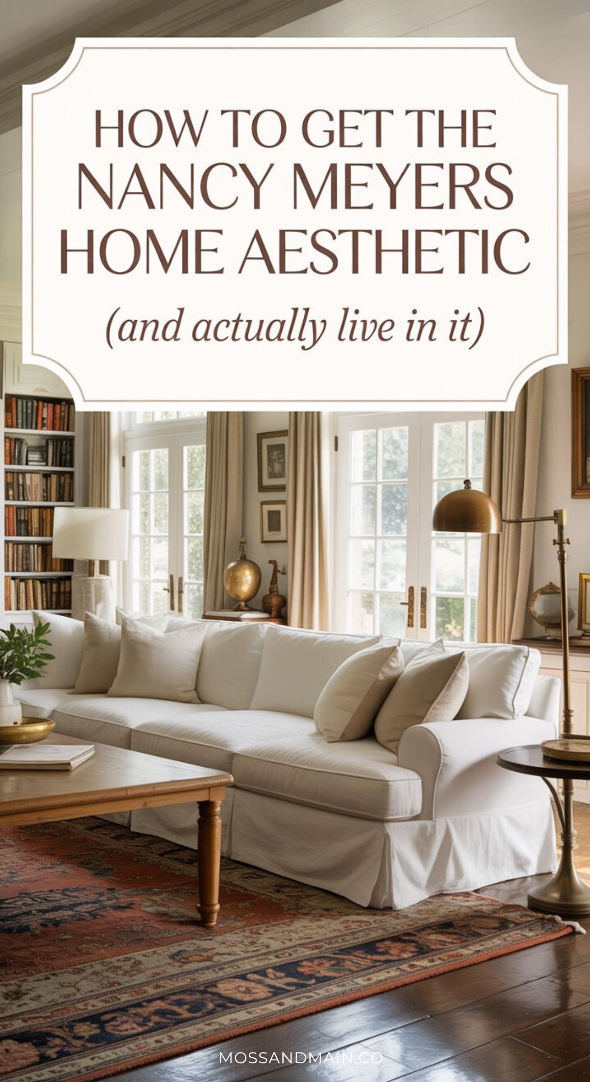 A bright, elegant nancy meyers living room featuring a white sofa, wooden coffee table, bookshelves, large windows with beige curtains, and a patterned rug. Overlaid text reads: “How to get the Nancy Meyers home aesthetic (and actually live in it).”.