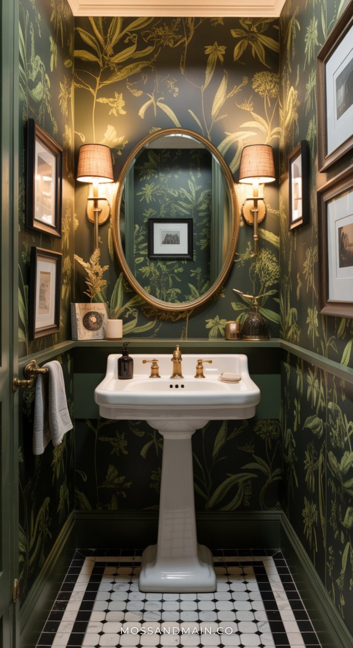 A moody bathroom featuring green botanical wallpaper, a white pedestal sink with gold fixtures, an oval mirror, elegant wall sconces, framed pictures, and classic black-and-white tile flooring.