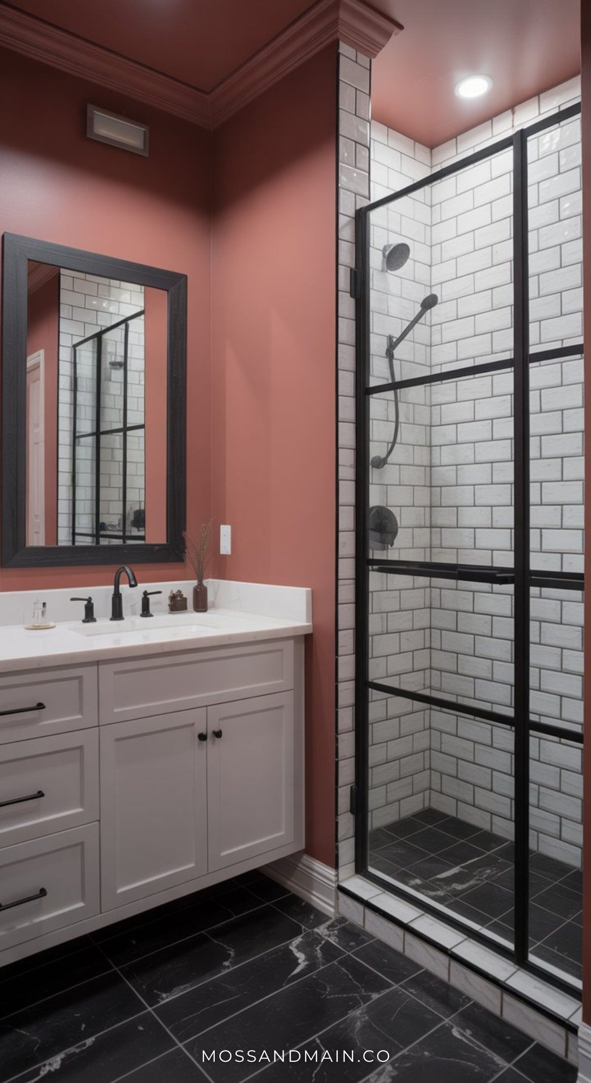 A stylish bathroom featuring a white vanity and sink, black faucet, large mirror, and a glass shower with white subway tiles and black grid frame. Deep terracotta walls and black floor tile create a bold bathroom look.