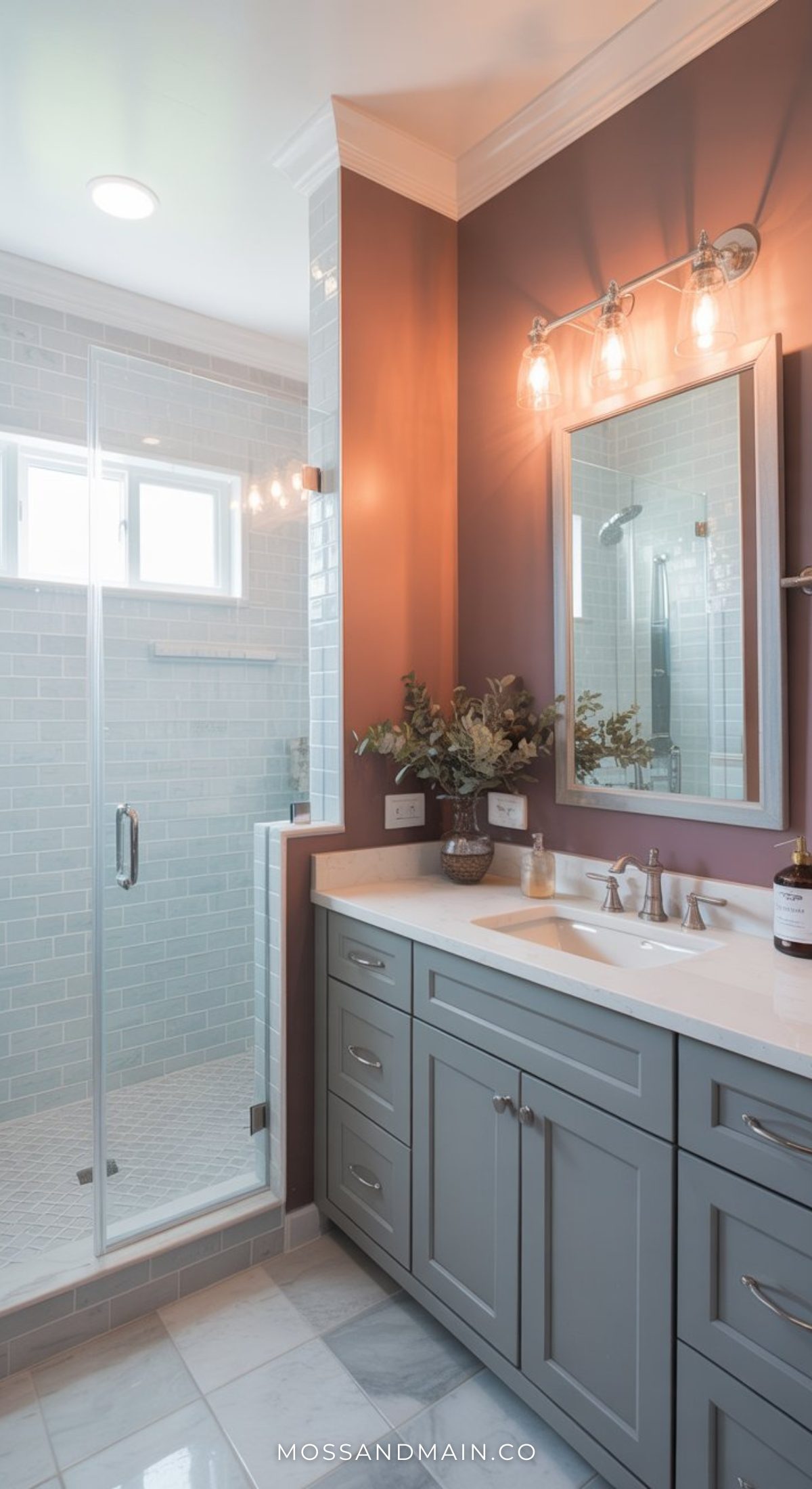 A modern bathroom with a glass-enclosed shower, light blue subway tiles, a double-sink vanity with gray cabinets, brass fixtures, and decorative lighting—perfect inspiration for stylish bathrooms and lovers of bold bathroom decor.
