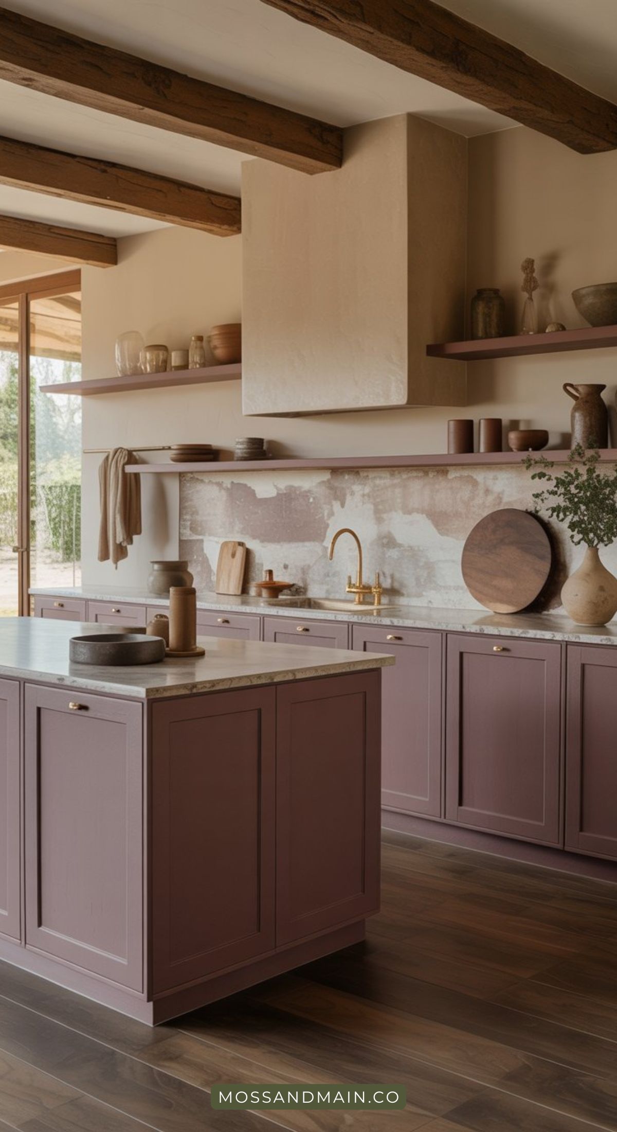 A modern kitchen with mauve and plum cabinets, marble countertops, wooden shelves holding ceramics, a gold faucet, and rustic wood beams on the ceiling. Natural light streams in from a large window.
