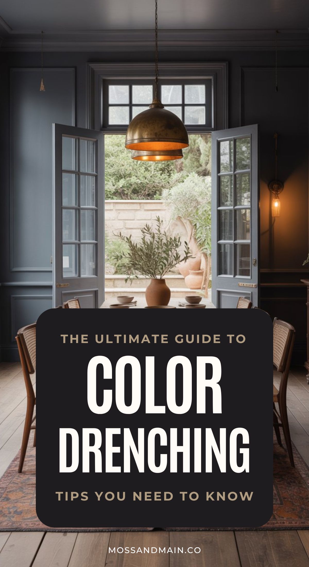 A stylish dining room with dark blue, color-drenched walls, a wooden table and chairs, copper pendant lights, and open French doors leading to a garden. Text overlay reads, The Ultimate Guide to Color Drenching: Tips You Need to Know.