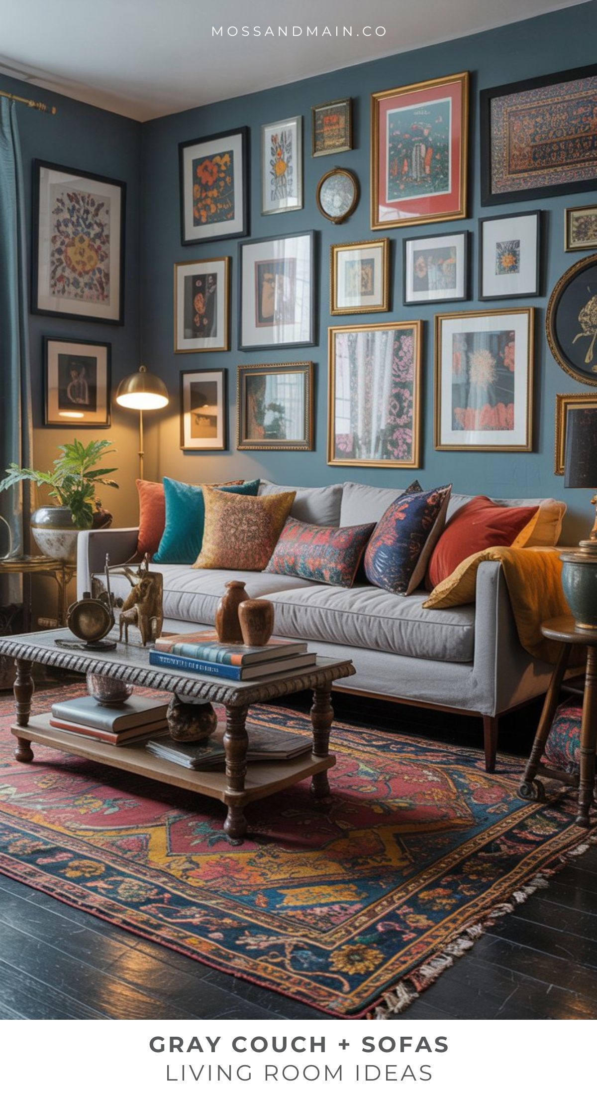 A stylish grey sofa living room with colorful pillows, patterned rug, wooden coffee table, indoor plants, and a gallery wall of framed art above the couch. The space exudes a cozy, eclectic feel.
