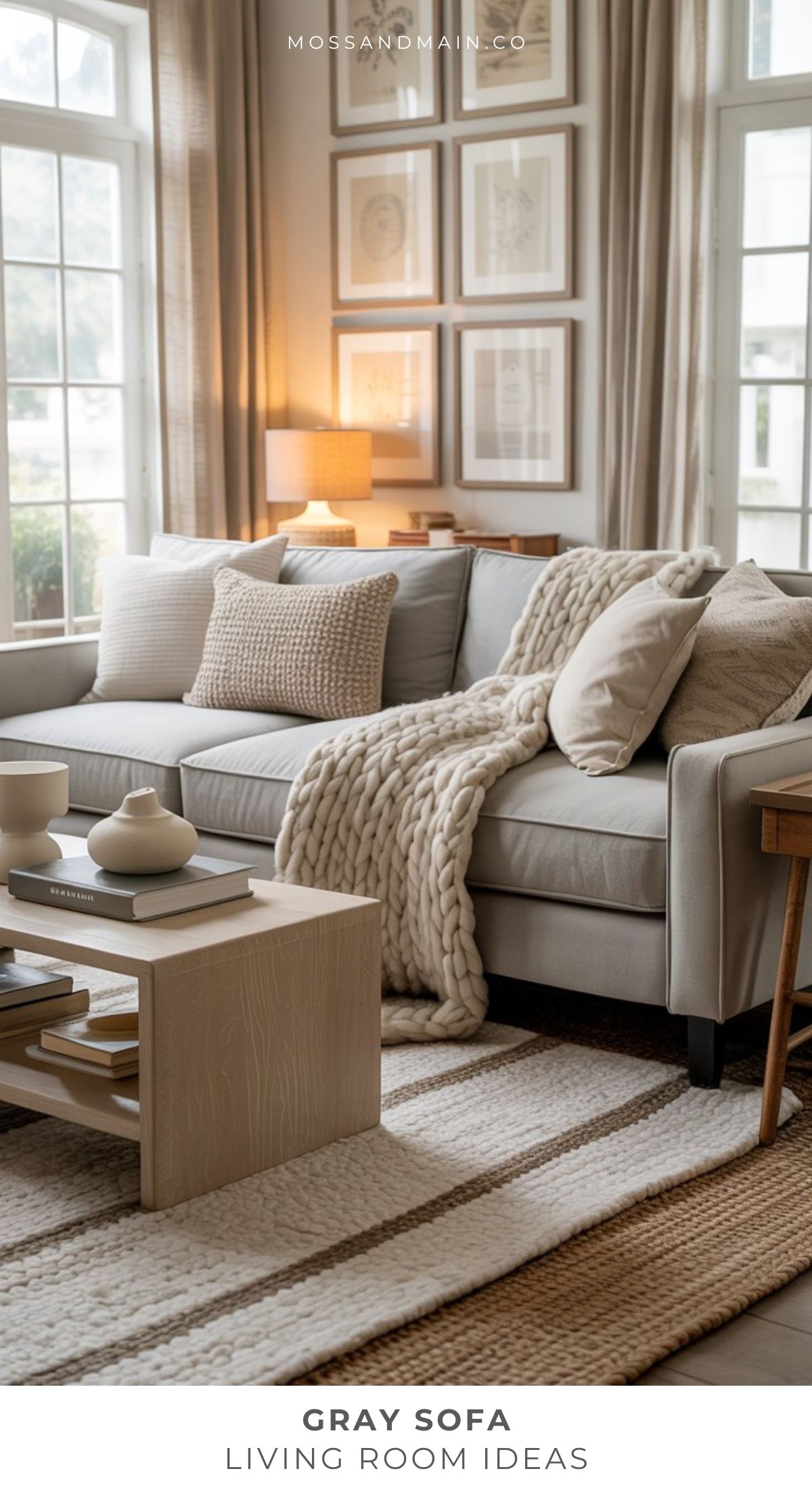 A cozy living room featuring a gray couch, neutral-toned pillows, and a chunky knit throw blanket. A light wood coffee table sits on a striped rug. Art prints and large windows inspire serene, modern living room ideas.