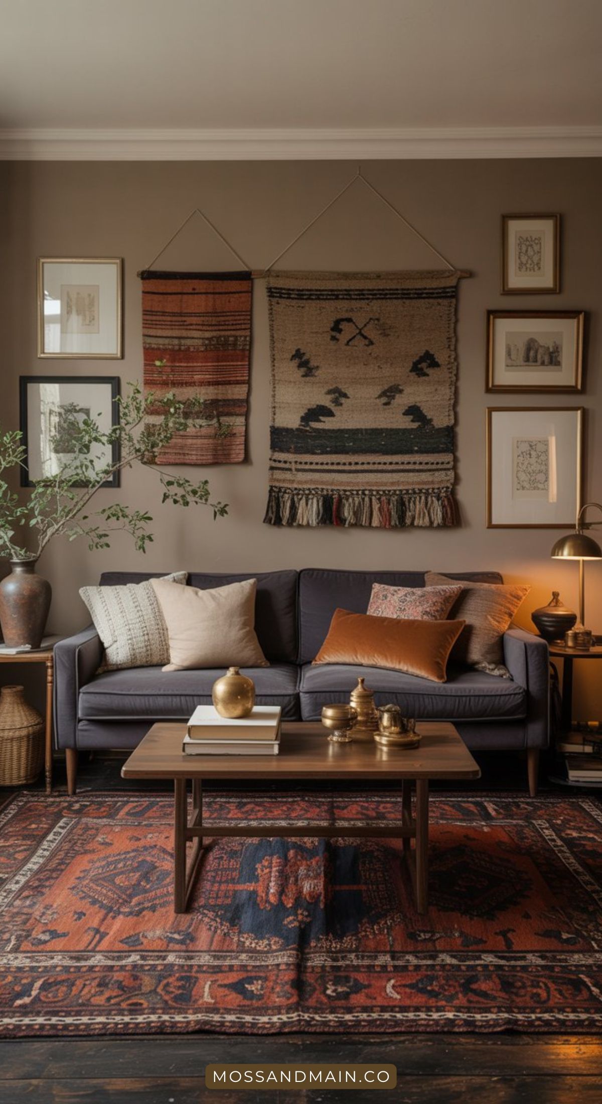A cozy gray couch living room features assorted pillows, a wooden coffee table, and warm decorative accents. Woven rugs and art hang on taupe walls, while earthy tones and plants add a welcoming touch.