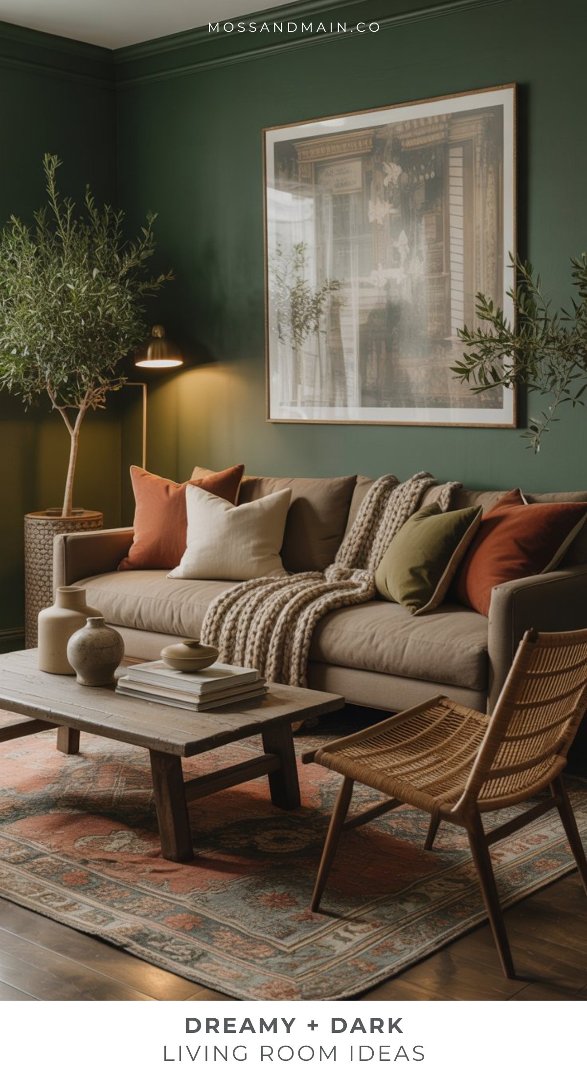 A moody living room with dark green walls, a beige sofa with earth-toned cushions and a knit throw, potted plants, a wooden coffee table, a wicker chair, and framed artwork above the couch creates the ultimate cozy retreat.