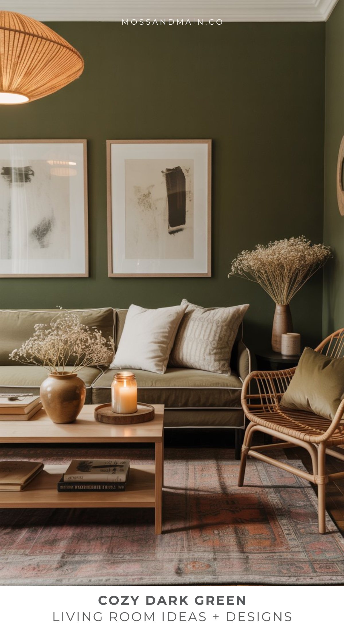 A cozy living room with dark green walls, a beige sofa with white cushions, a wooden coffee table with candles and vases, rattan chair, dried flowers, framed art, and a patterned rug—perfect for moody living room inspiration.