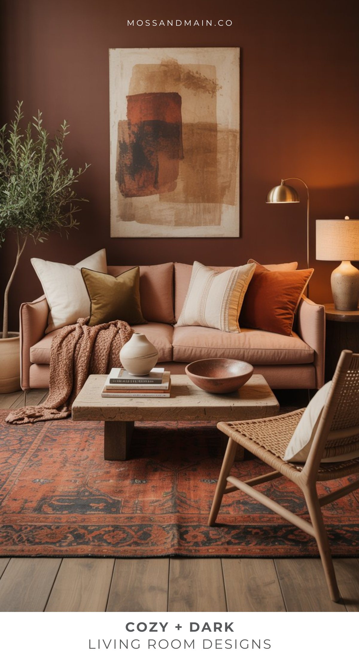 A moody living room with a blush sofa, earth-toned cushions, a textured blanket, wooden coffee table, and woven chair. Warm brown walls, modern art, an indoor plant, and cozy lighting complete this inviting space.