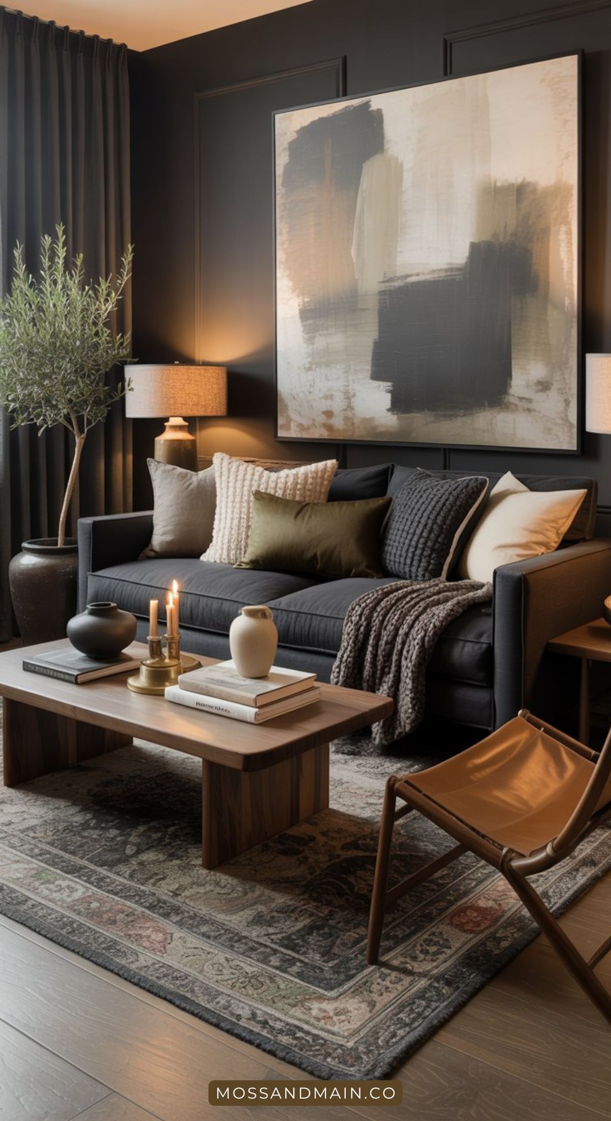 A modern dark living room features a dark sofa, neutral cushions, and a textured blanket. A wooden coffee table holds candles and ceramics, while abstract art decorates the wall and a potted plant stands by. Warm lighting creates a cozy atmosphere.
