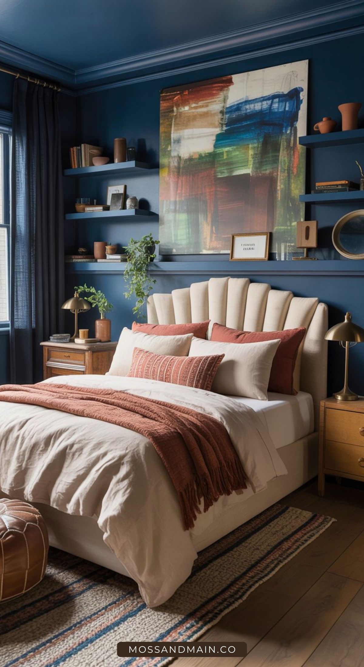 A cozy, color-drenched bedroom with blue walls, a beige upholstered bed, rust-colored pillows and throw, wooden nightstands, floating shelves with decor, and a colorful abstract painting—perfect inspiration for maximalist bedrooms.