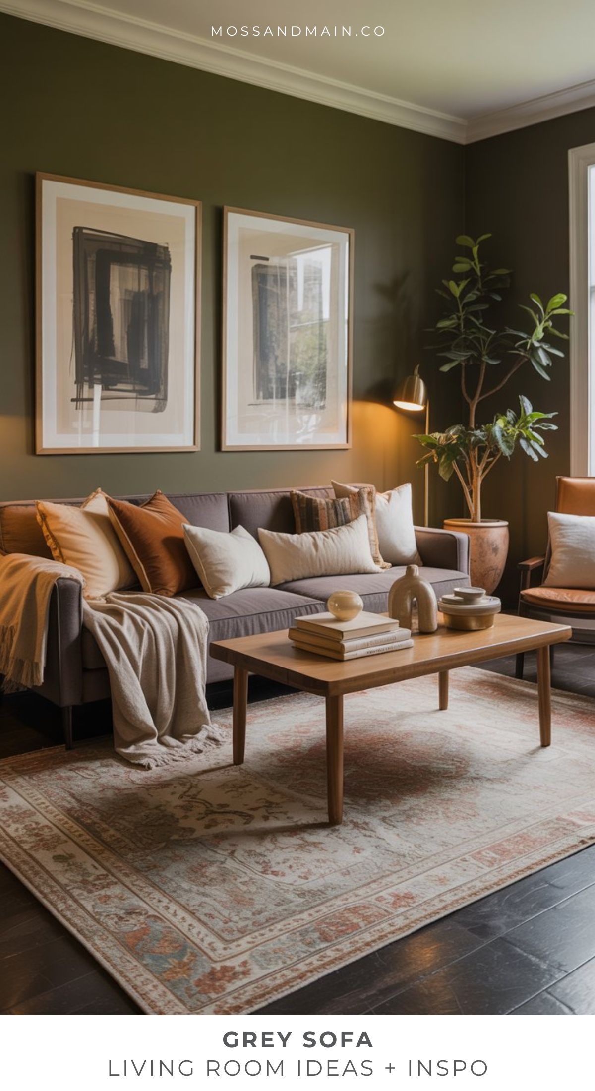 A modern grey sofa living room with neutral pillows, a wooden coffee table with decor, wall art, a tall plant, floor lamp, and an area rug on dark flooring. The space has a calm, stylish, and cozy atmosphere.