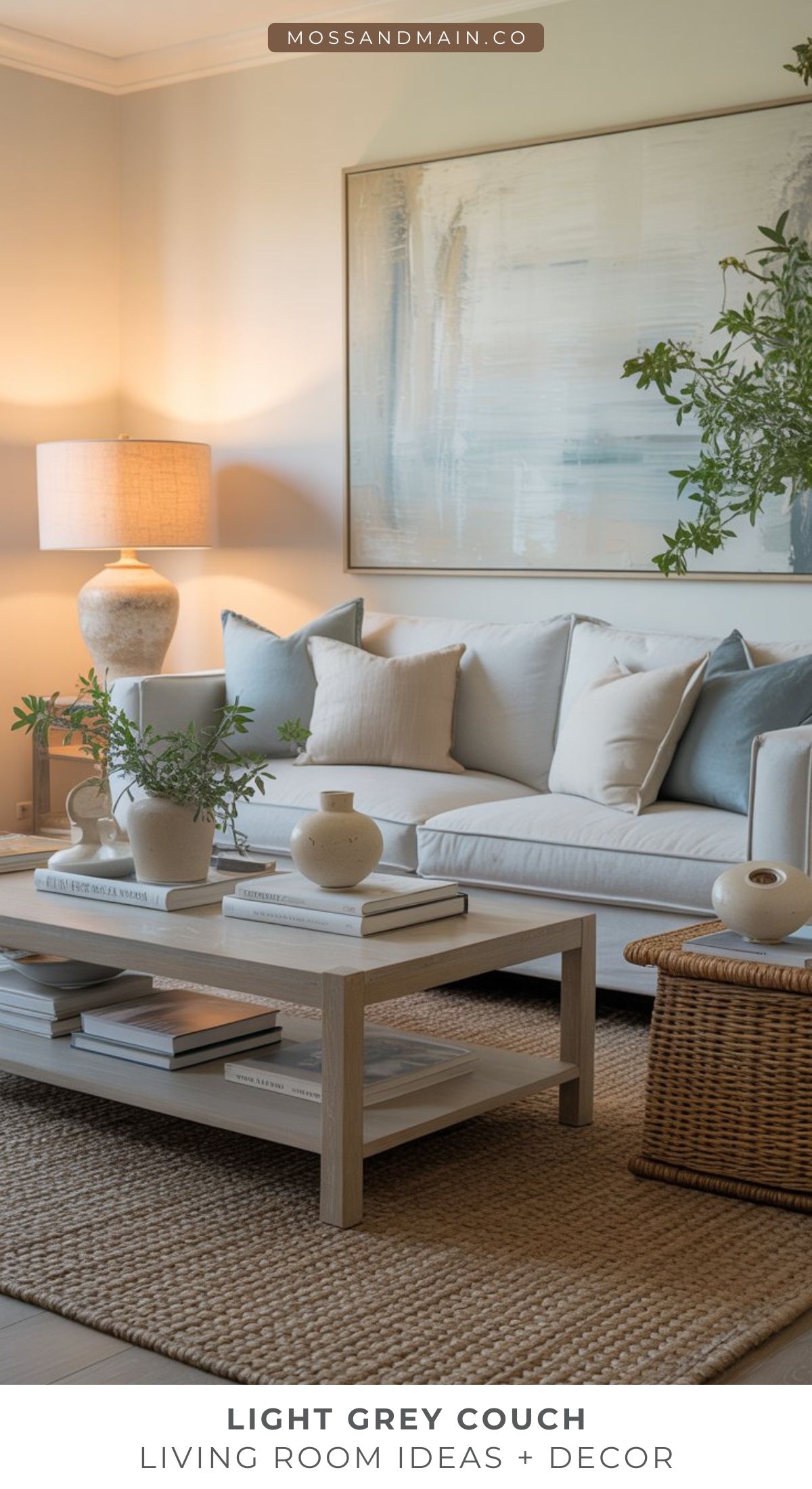 A stylish living room features a light gray couch with assorted pillows, a wooden coffee table with vases and books, a woven rug, framed artwork, and a ceramic lamp—perfect inspiration for cozy living room ideas with modern decor.