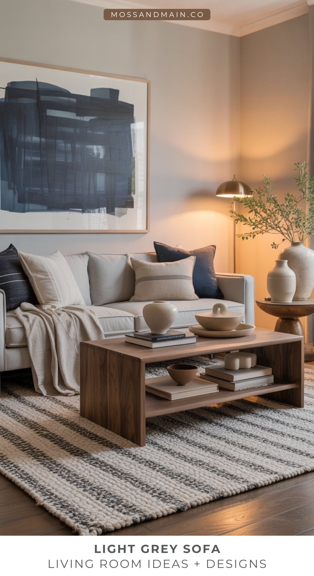 A modern living room with a light gray couch, navy and cream pillows, a striped rug, cozy wooden coffee table with neutral decor, a large abstract painting, and a leafy plant in the corner—perfect for inspiring new living room ideas.