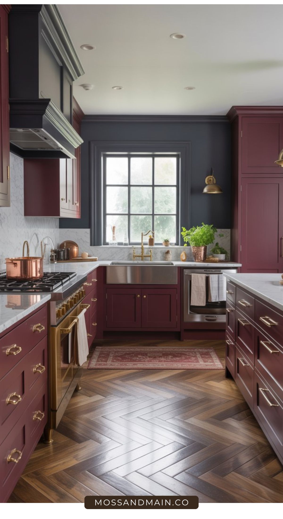 A stylish kitchen with burgundy cabinets inspired by modern Aubergine Kitchen Ideas, brass hardware, marble countertops, a large farmhouse sink, stainless steel appliances, wooden herringbone floors, and a big window letting in natural light.