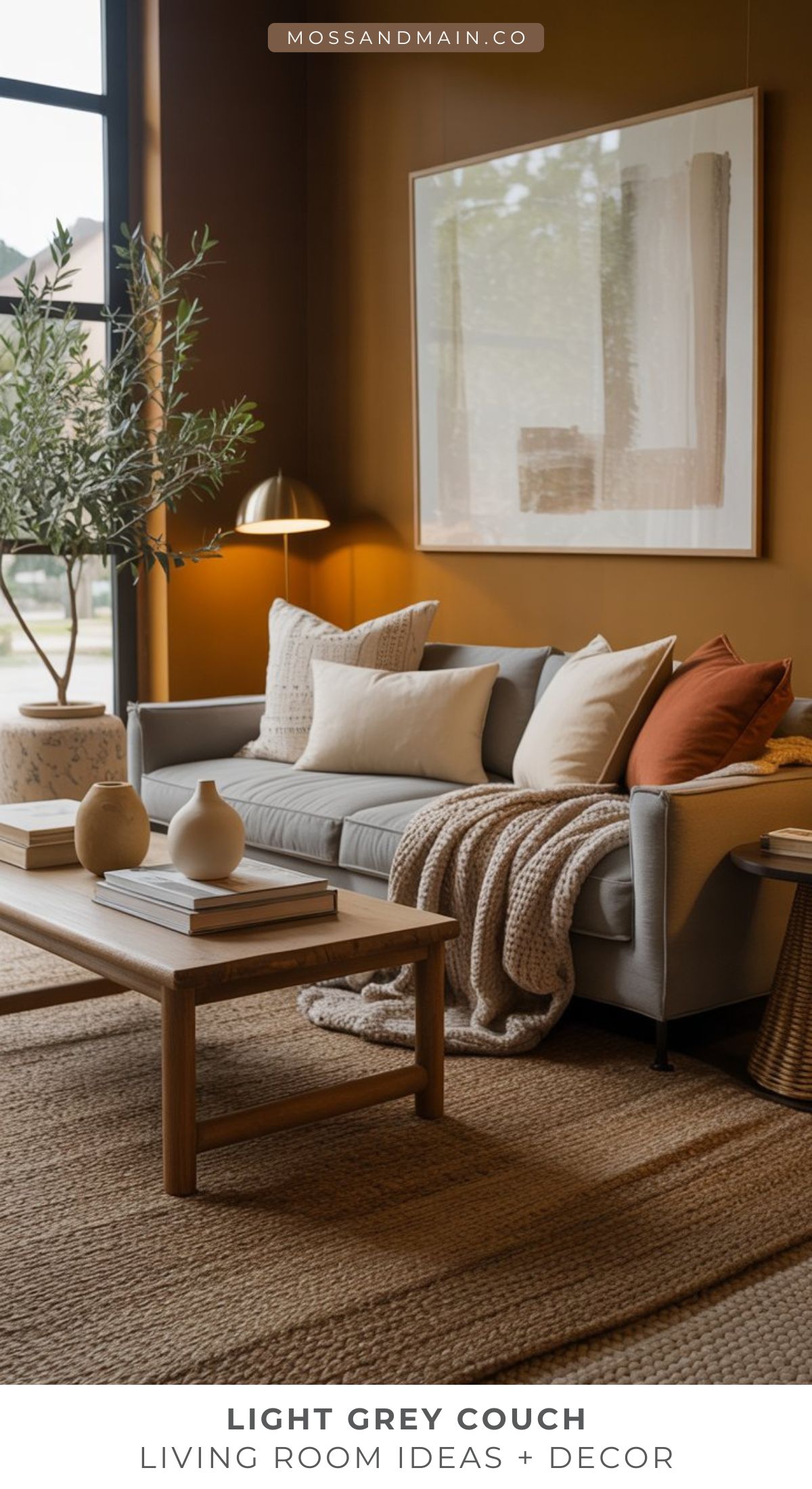 A cozy living room with a light gray couch, beige and rust pillows, a knit blanket, wooden coffee table with books and vases, large abstract artwork, indoor plant, and neutral-toned decor—perfect for those seeking inspiring living room ideas.
