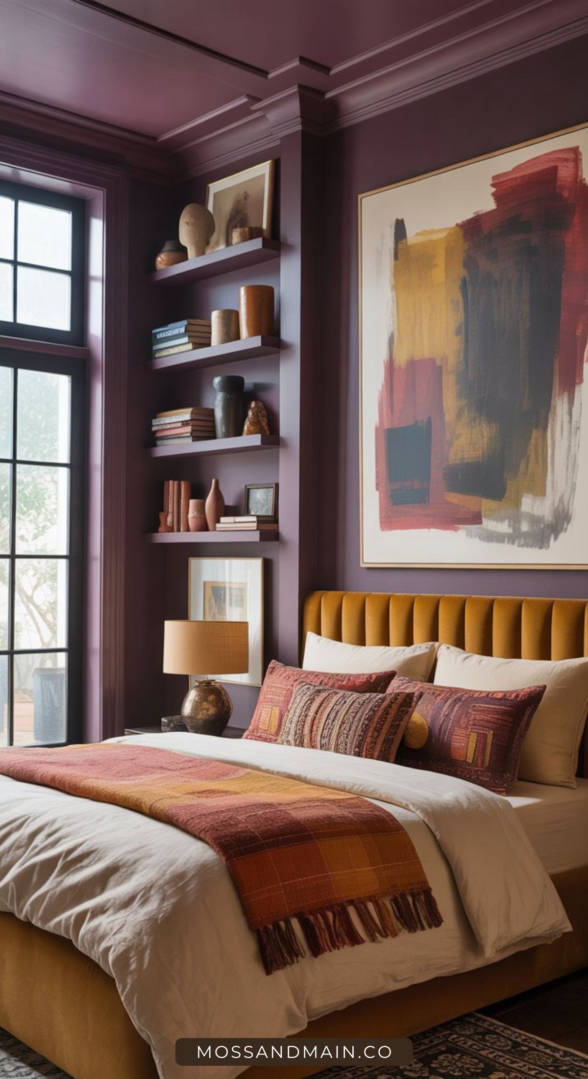 A cozy bedroom with deep purple walls, mustard yellow upholstered bed, colorful bedding, a modern abstract painting, shelves with books and decor, and large windows letting in natural light.