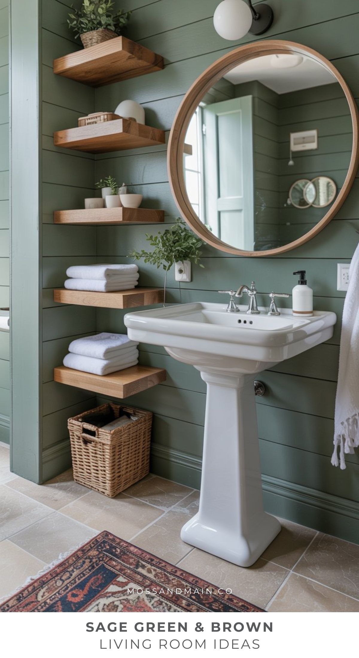 A cozy bathroom with sage green shiplap walls, floating wooden shelves, a round mirror, a white pedestal sink, and a wicker basket creates a calm, natural look that feels both inviting and timeless.