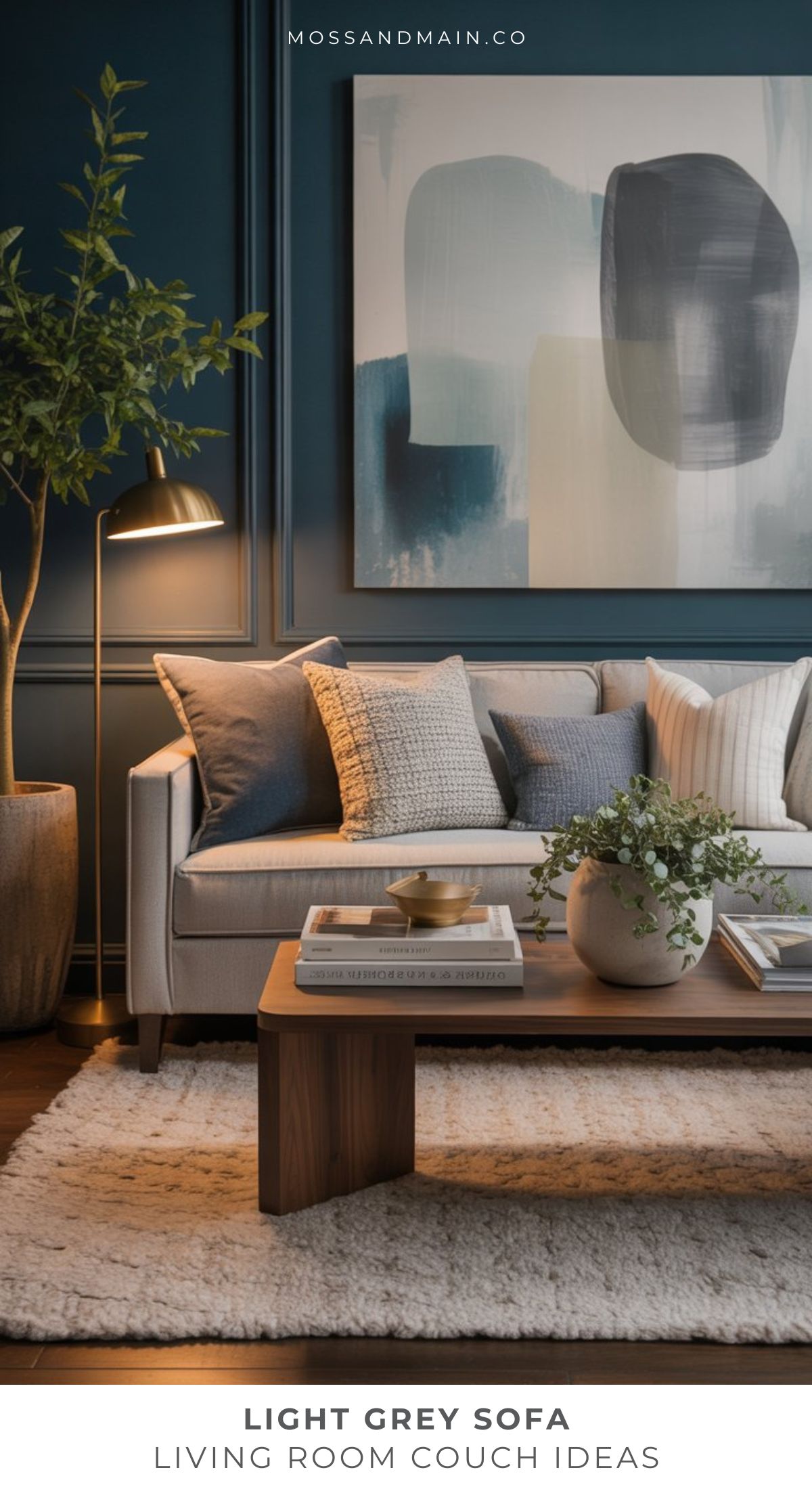 A modern living room with a cozy light gray couch, assorted throw pillows, a wooden coffee table with decor, a potted plant, floor lamp, and abstract wall art, set against dark blue paneled walls and a textured rug—perfect for fresh living room ideas.