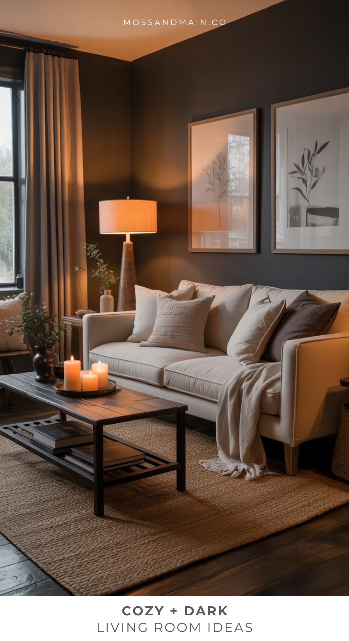 A cozy, moody living room with dark walls, a light sofa with pillows and a throw blanket, a coffee table with candles, floor lamp, neutral decor, framed art, and a large window with curtains letting in natural light.