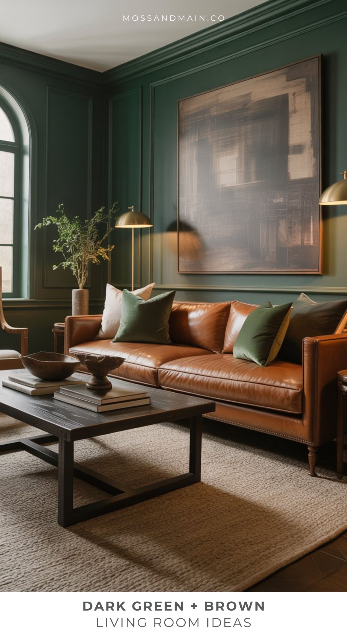 A stylish green living room with dark green walls, a brown leather sofa with green pillows, a wooden coffee table, modern tableware, framed artwork, and a large window. Text reads Dark Green + Brown Living Room Ideas for a cozy living room space.