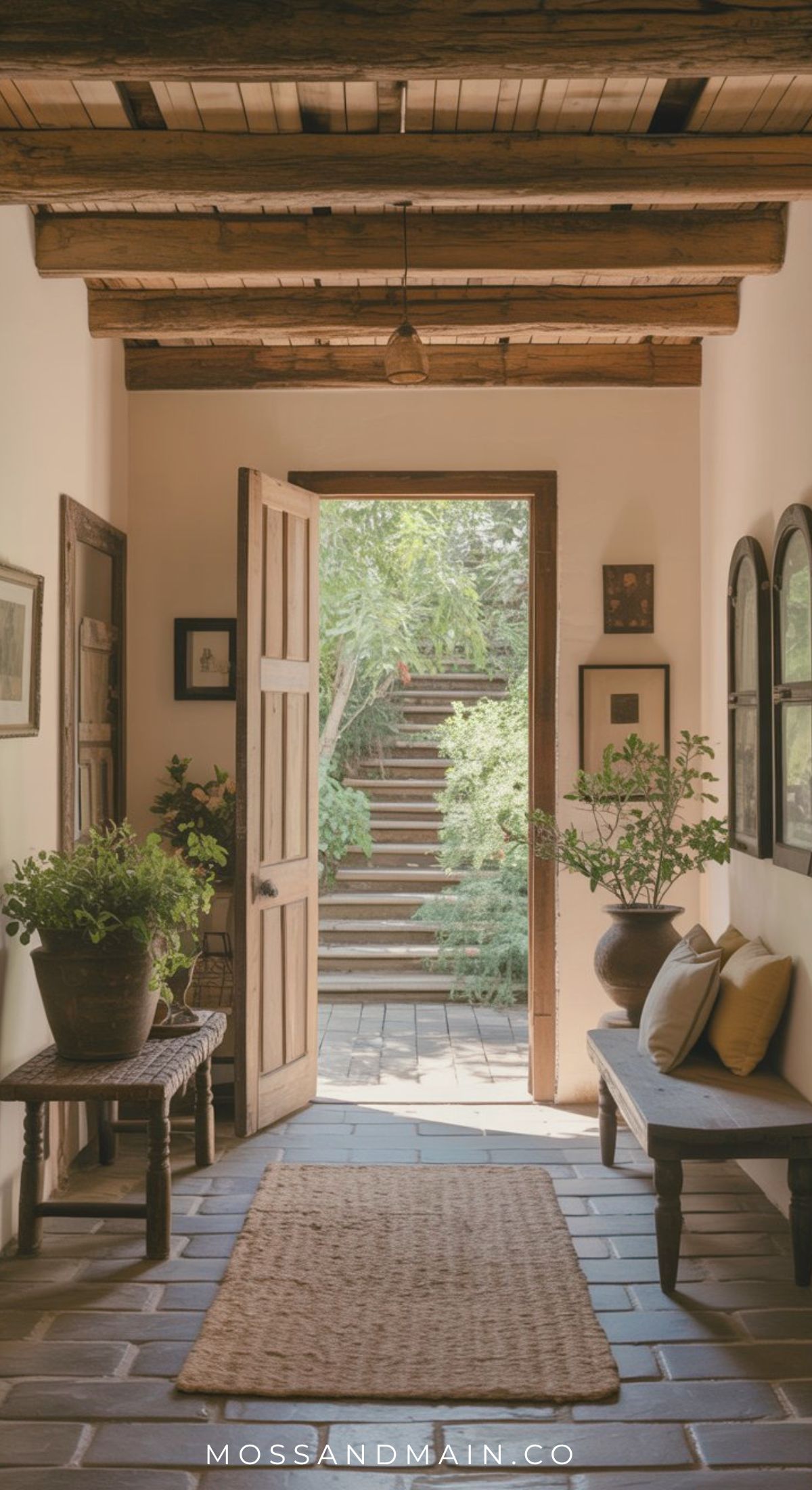 A warm entryway with wooden beams, potted plants, a woven rug, and a bench with cushions leads to an open door revealing a sunlit garden—perfect inspiration for rustic entryway ideas.