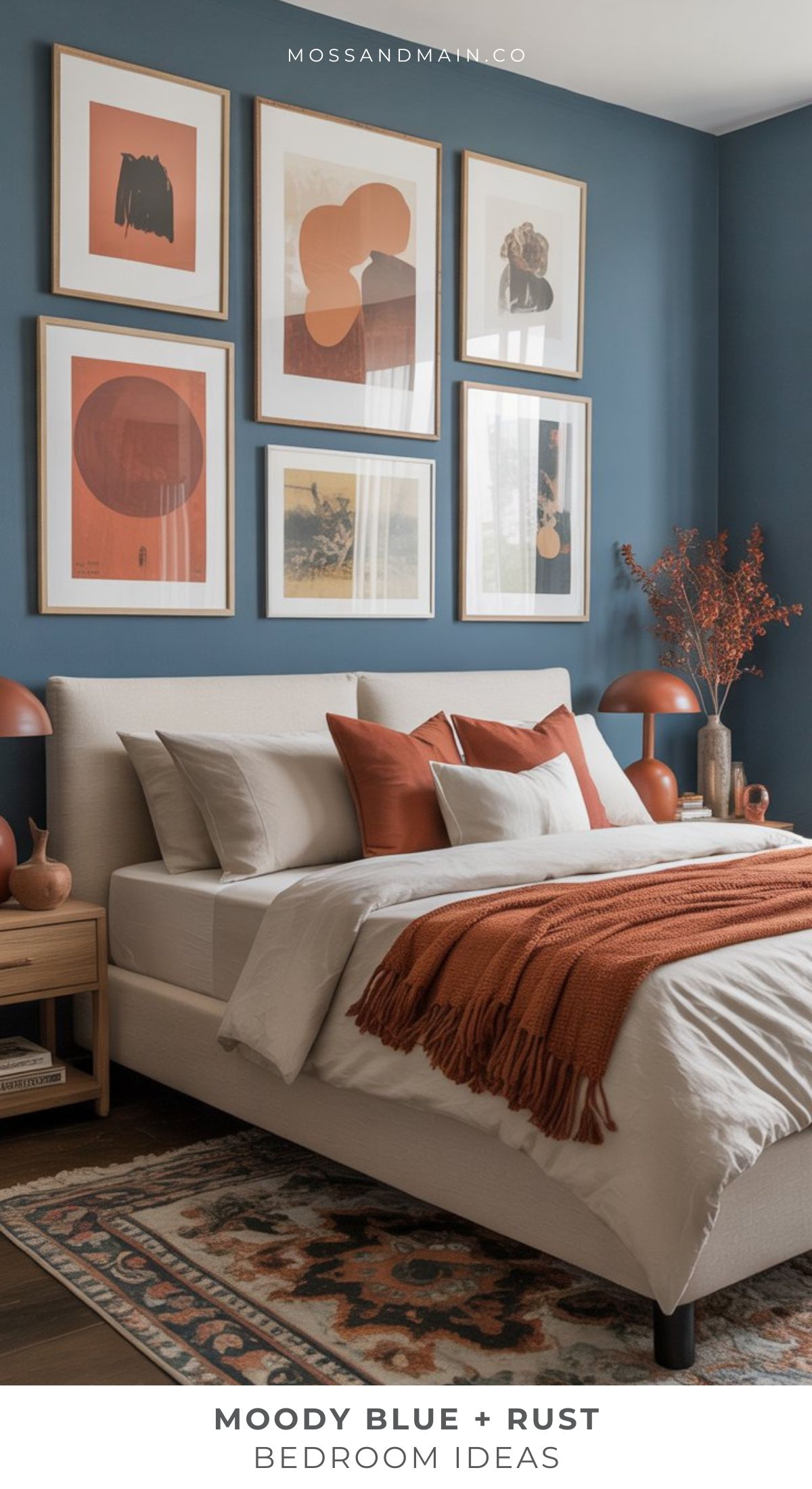 A modern Rust bedroom with moody dusty blue walls, rust-colored accents, beige bedding, and a rust throw blanket. Abstract art forms a gallery wall above the bed, while wooden nightstands and dried floral decor add earthy bedroom ideas for a cozy feel.