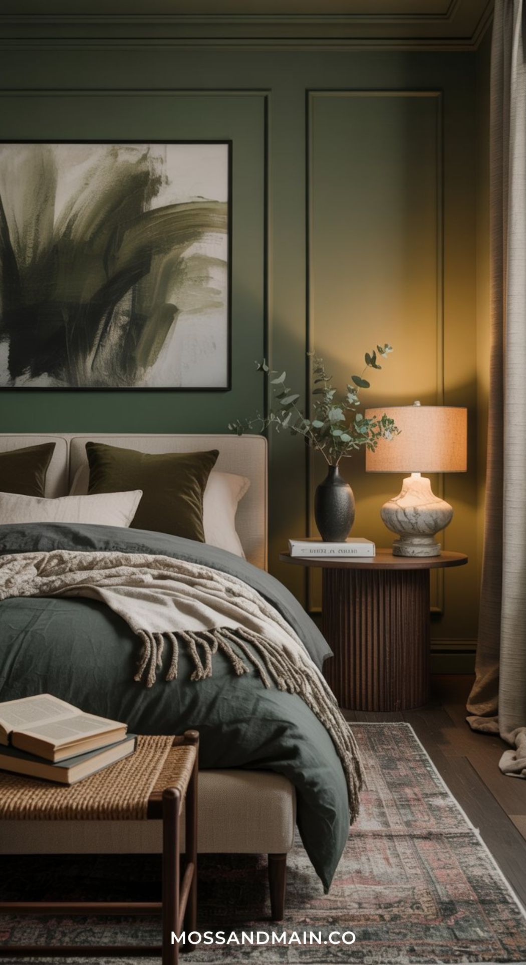 A cozy, layered bedroom with olive green walls, green and cream bedding, a textured blanket, side table with lamp, books, greenery-filled vase, large abstract painting, and soft natural light create the perfect Green Boho Bedroom retreat.