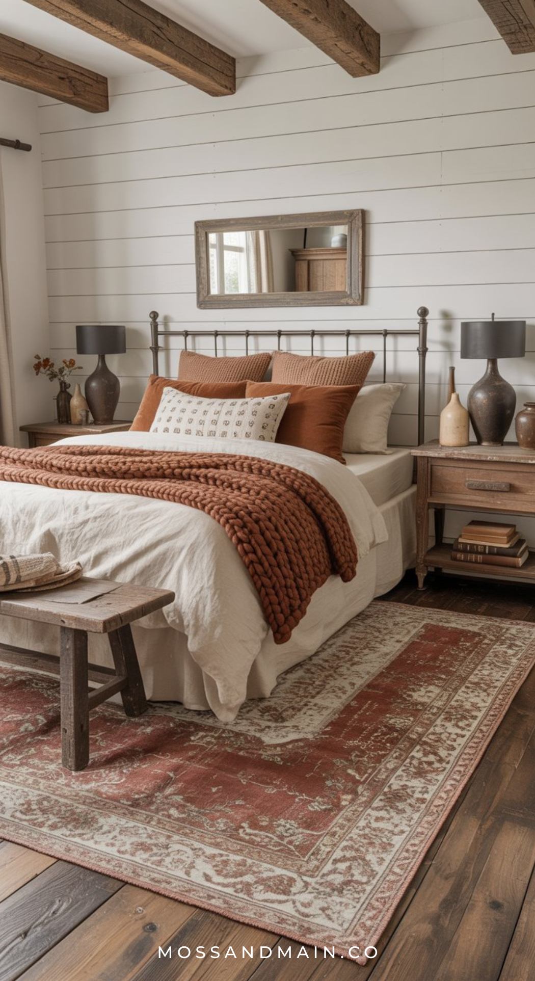 Cozy bedroom with white shiplap walls, wooden beams, a metal bed frame, rust-colored bedding, and two wooden nightstands—perfect inspiration for Brown Bedroom Ideas. Moss and Main branding at the bottom.
